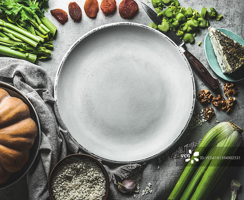 健康食材背景，包含蔬菜、米饭、杏干、奶酪和芹菜，灰色厨房桌面上摆放着空盘子图片素材