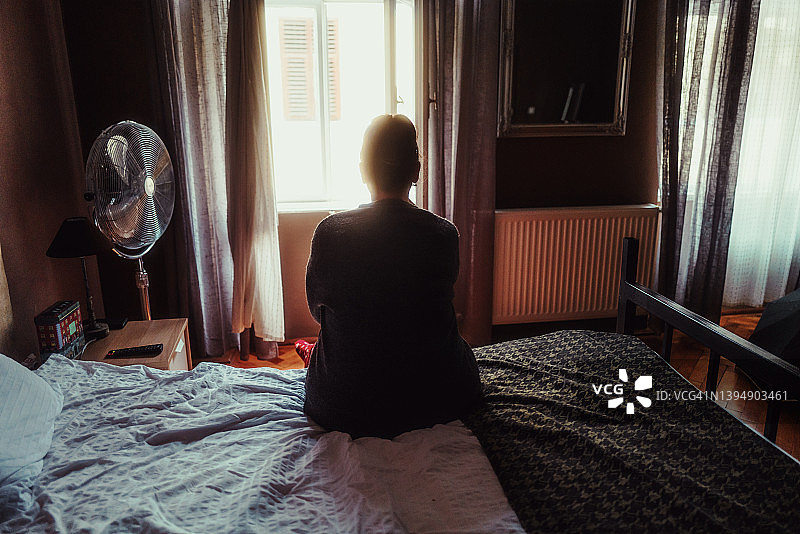 独自坐在酒店房间床上悲伤的女人图片素材