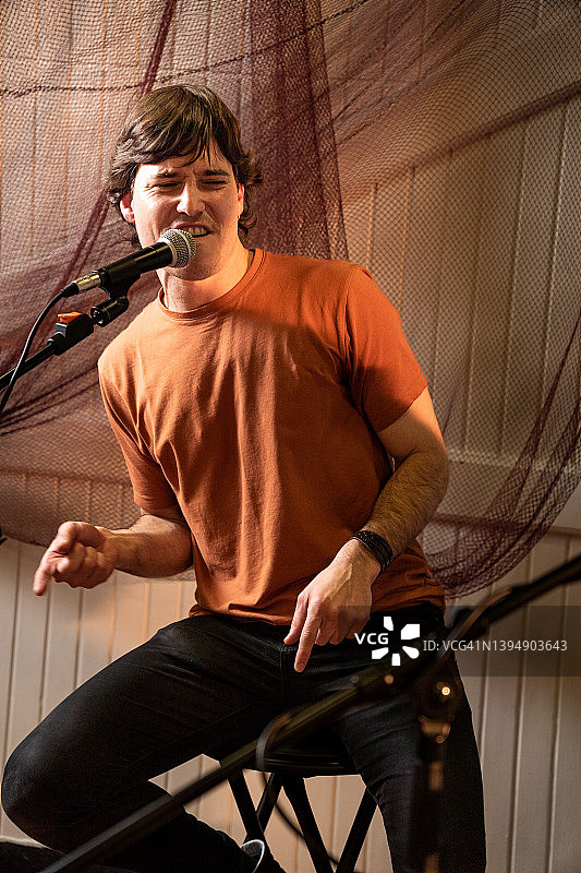 快乐的年轻男歌手在酒吧演唱，卡拉OK图片素材