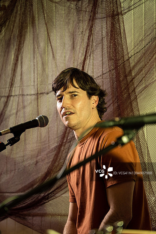 在酒吧音乐会上唱歌的歌手肖像，有色光照明图片素材