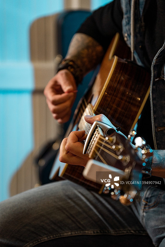 在酒吧音乐会上弹吉他的纹身吉他手特写图片素材