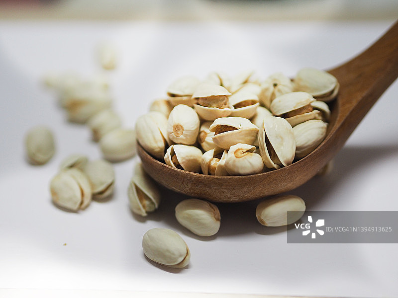 白色背景木勺中的开心果干图片素材
