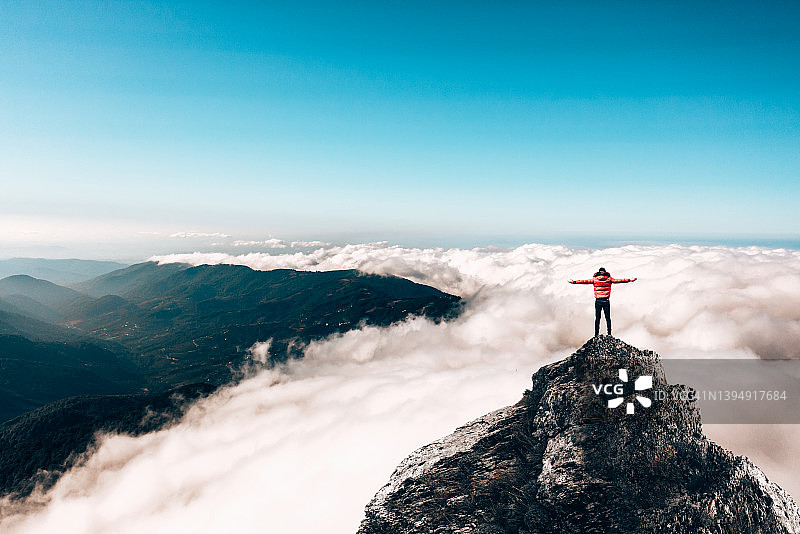 徒步旅行者在山顶欣赏云景，实现了梦想。图片素材