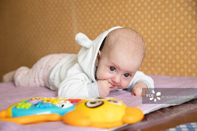 躺在柔软毯子上、儿童玩具旁的婴儿图片素材