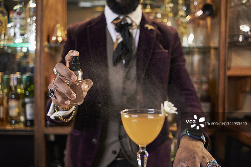 匿名调酒师在鸡尾酒中加入香氛喷雾图片素材