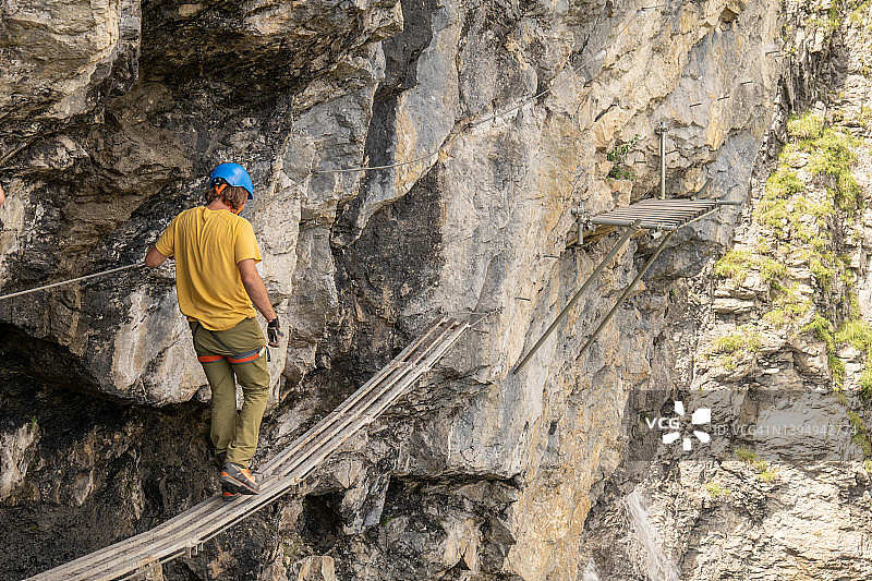 男子攀登铁索栈道，夏季活动概念图片素材