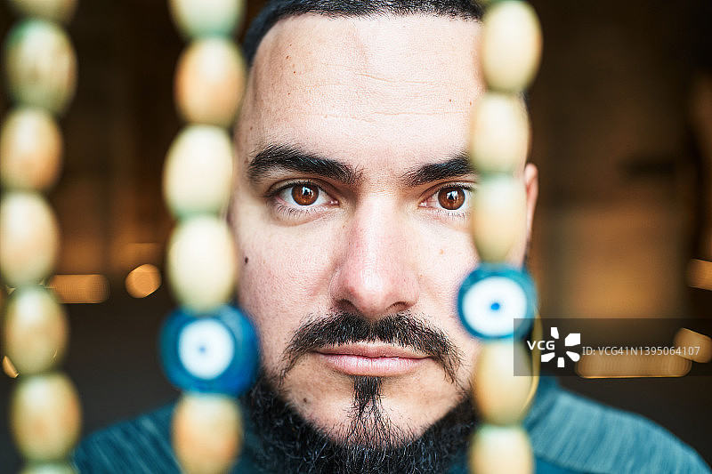 在彩色珠帘附近的胡子男人图片素材