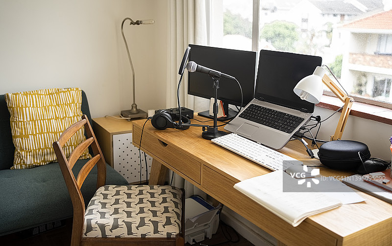 家里的播客工作室设置，桌子上有麦克风和电脑图片素材