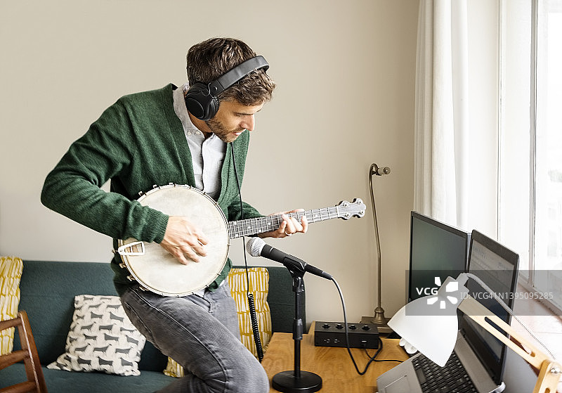 男人在家中录音室弹奏班卓琴图片素材