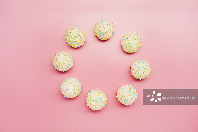 粉色背景上排列成圆圈的糖果图片素材
