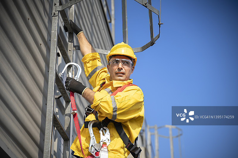 在高处作业时佩戴安全带和安全绳的建筑工人图片素材