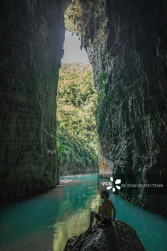 男人坐在岩石上，眺望墨西哥恰帕斯州的碧绿河流与时间之弧图片素材