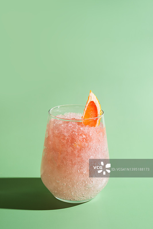 绿色背景上盛有融化冰块、葡萄柚和薄荷的夏日清爽气泡饮品图片素材