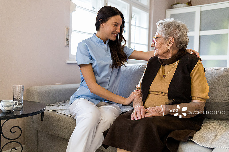 年轻护士在病人家中与年长病人交谈图片素材