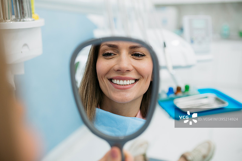 快乐的女人在手持镜中看着自己。图片素材