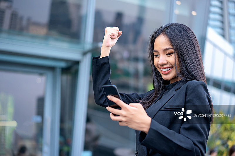 站着查看智能手机信息的欢呼兴奋女商人图片素材