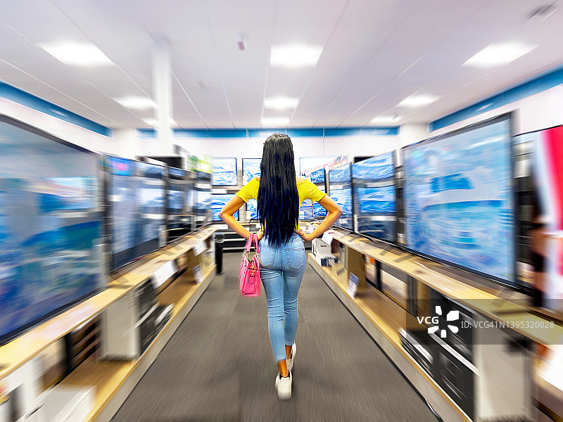 年轻女人行走在电器商店中图片素材