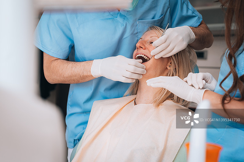 牙医的手检查女病人牙齿的特写图片素材