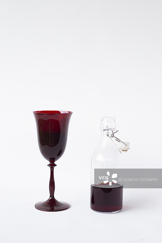 装有葡萄酒的红色玻璃杯和瓶子图片素材