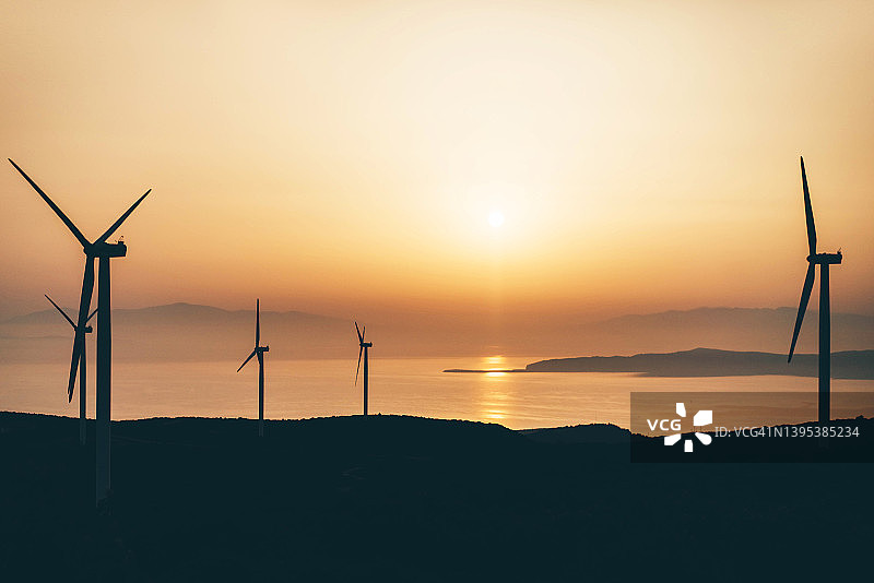 日落时山丘上的风力涡轮机图片素材