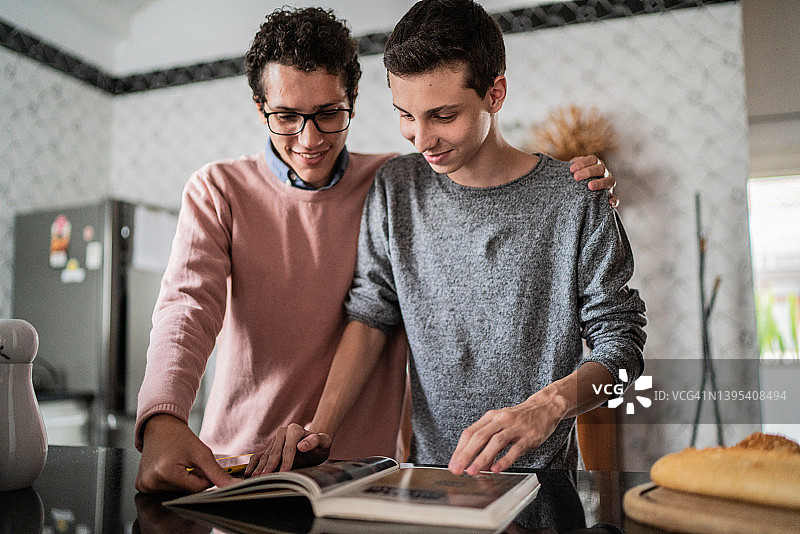 在家看家庭相册或烹饪书的兄弟图片素材