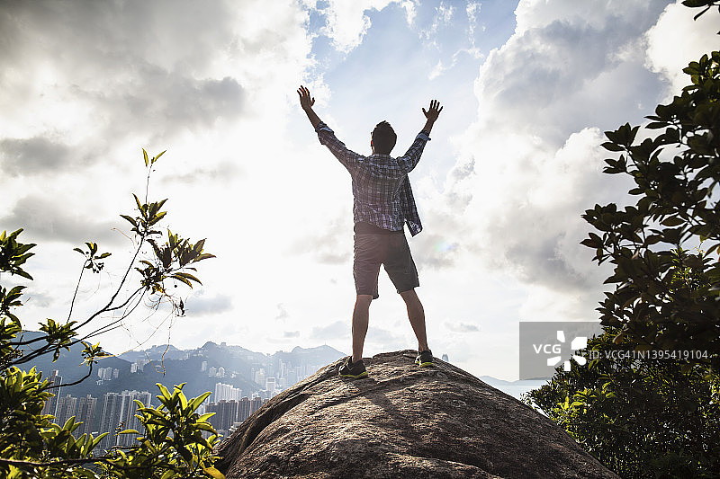 在香港的岩层上举起双臂的男人图片素材
