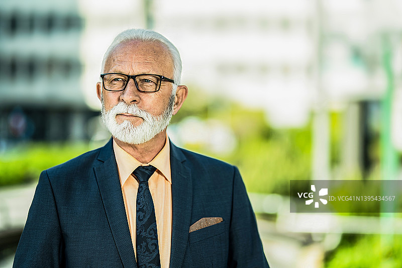 自信的年长商人站在城市街道上图片素材