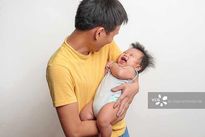 亚洲父亲在白色背景下抱着新生婴儿图片素材