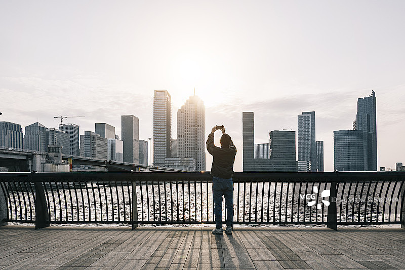 旅行者在城市天际线下用手机自拍图片素材