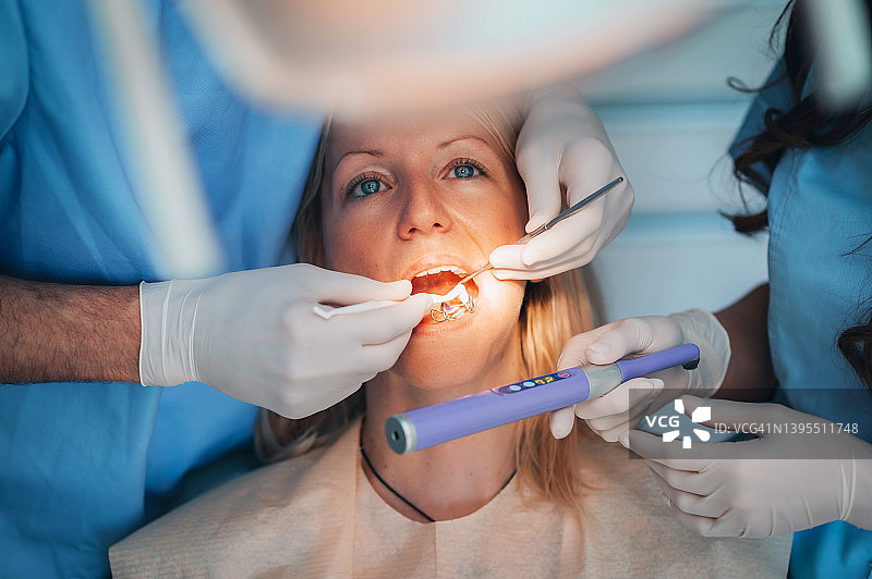 牙医和助手为女患者进行牙齿治疗。图片素材