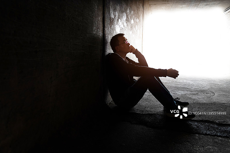 男子坐在黑暗的隧道里图片素材