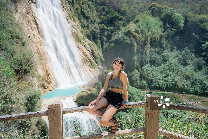 女人坐在墨西哥恰帕斯州埃尔奇夫隆瀑布附近的栅栏上图片素材
