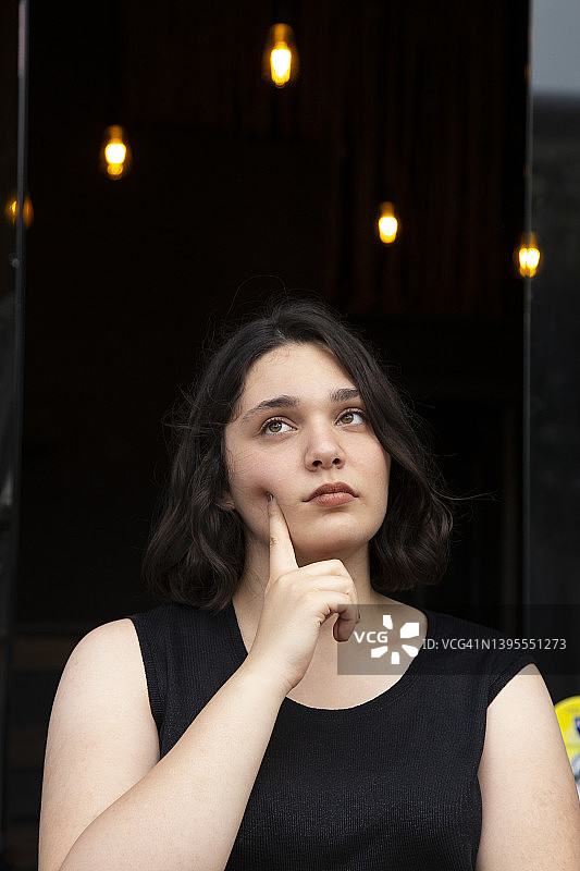 灯光下，沉思的年轻女人肖像图片素材