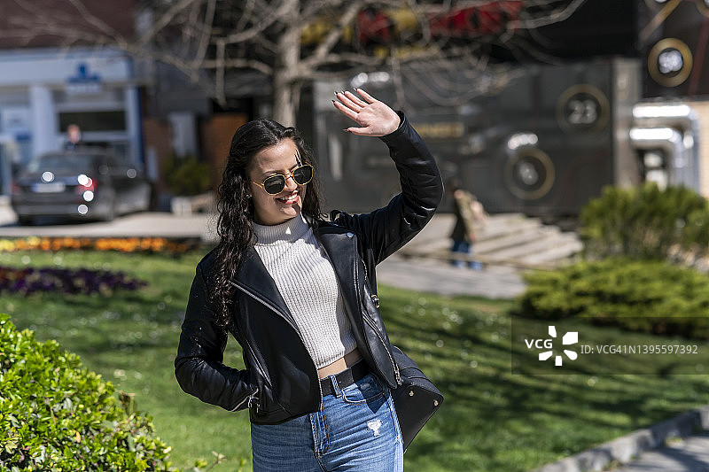 美丽的棕发少女向朋友挥手图片素材