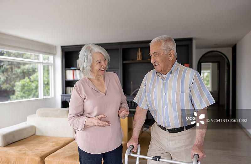 快乐的年长夫妇在家，男人用助行器走路图片素材