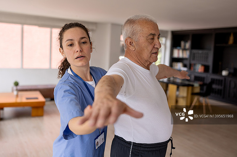 理疗师帮助老年男性居家康复图片素材