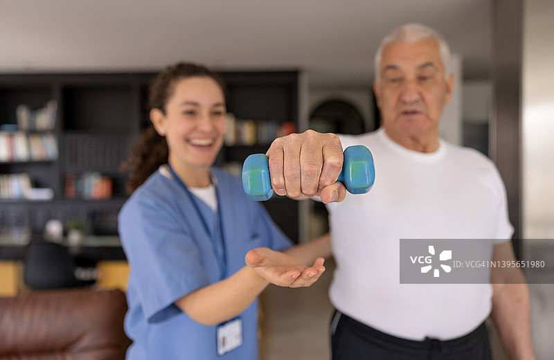 理疗师帮助老年男人在家中康复图片素材