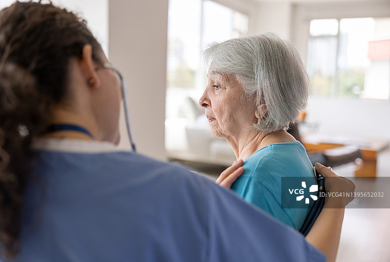 医生上门拜访并听诊老年妇女的心脏图片素材