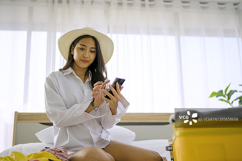 年轻女子在卧室里准备旅行用品图片素材