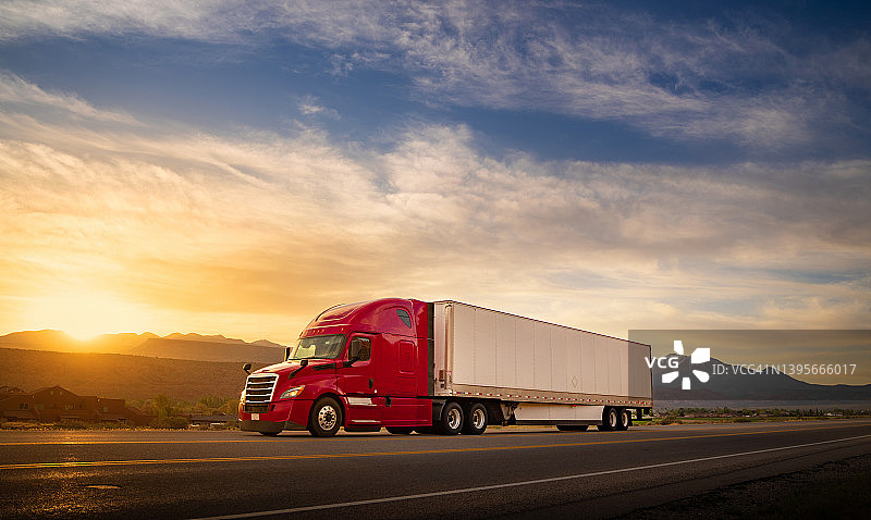 美国单车道公路上日出时疾驰的红白半挂卡车图片素材