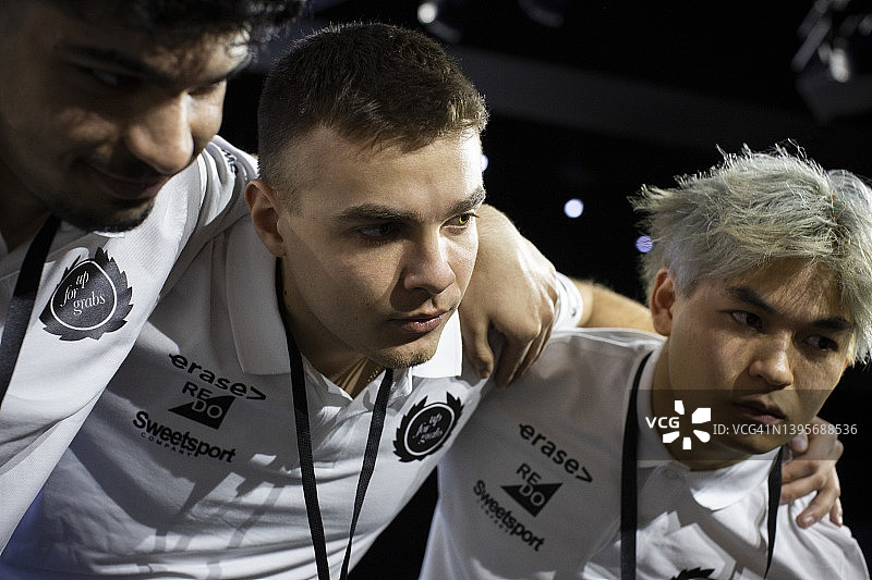 在电竞竞技场上互相搂抱的多种族男性游戏玩家图片素材