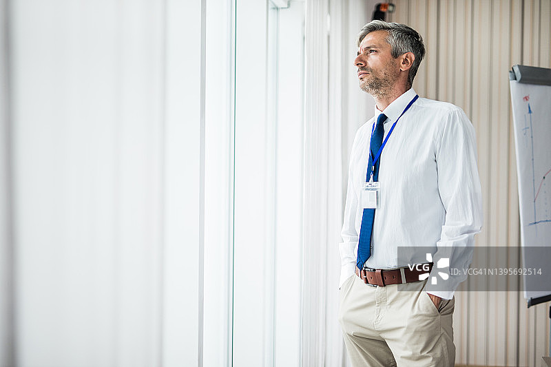 表情严肃的中年商人望向窗外图片素材