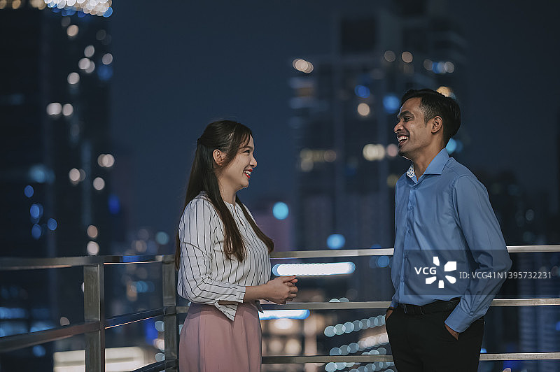 下班后在办公楼外阳台走廊交谈的亚洲同事图片素材