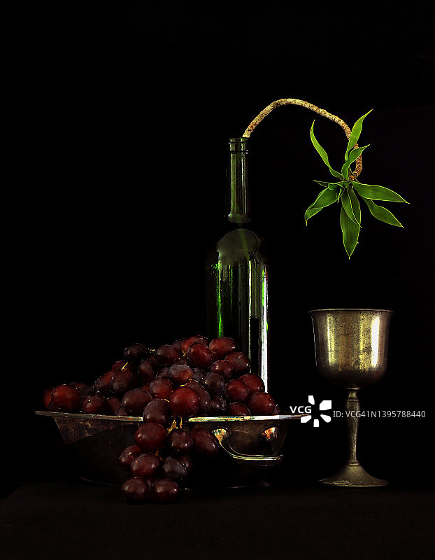 碗里的一串红葡萄、瓶子里的植物和失去光泽的葡萄酒杯图片素材