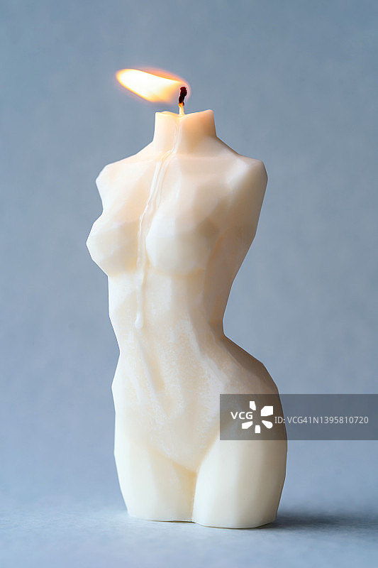 灰色背景上美观女性身体形状的燃烧大豆或蜡烛，女性气质和美丽的概念图片素材