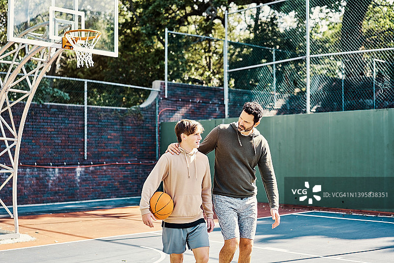 打完篮球后行走的父子。年轻男人和青少年玩得开心，保持健康和活力图片素材