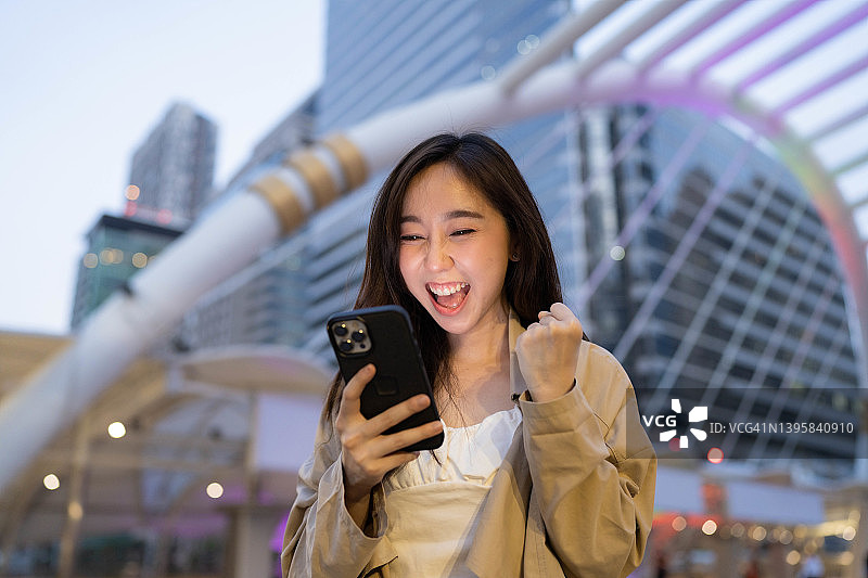 美丽的亚洲女商人看手机，非常高兴图片素材