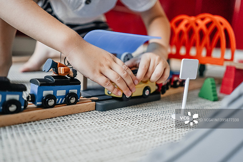 小男孩在家里的地板上玩铁木轨道图片素材