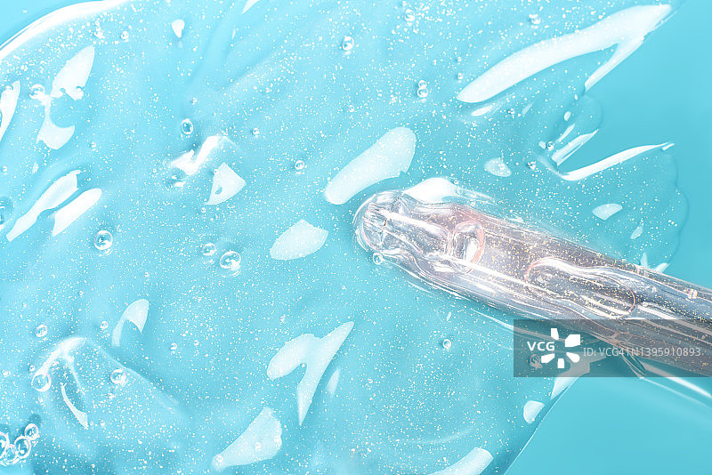 化妆品滴管末端，含精华液或透明质酸或精油，蓝色背景图片素材