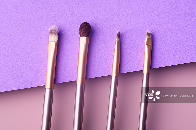 粉色和紫色背景上的银色和金色化妆刷俯视图图片素材